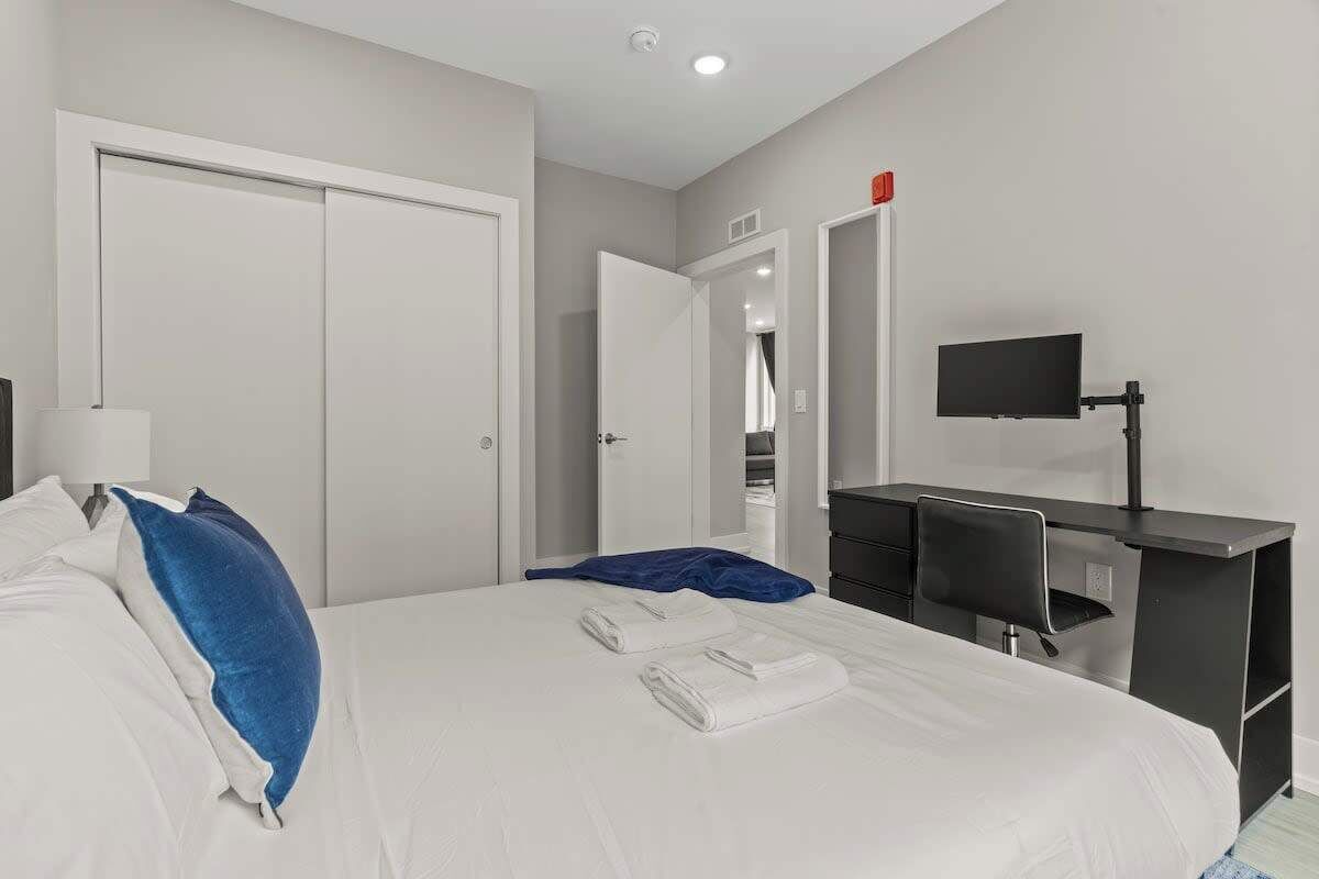 Een hotelkamer met een bed, een bureau, een stoel, een televisie en een kledingkast.