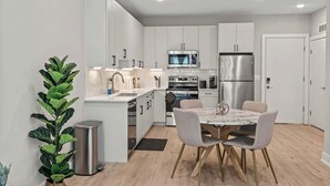 A modern kitchen with white cabinetry, stainless steel appliances, and a dining area with a marble table and chairs. - Luxury 1BD | 3 Beds | Northern Liberties (Philadelphia)