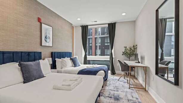 A hotel room with two beds, a desk, and a large window. - Luxury 1BD | 3 Beds | Northern Liberties (Philadelphia)