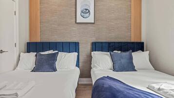 A hotel room with two beds, a wooden accent wall, and a framed artwork above the beds.