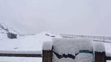 A snow-covered outdoor area with a wooden fence and a metal railing.