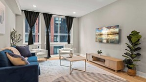 Ein modernes Wohnzimmer mit einer Couch, Sesseln, einem Couchtisch und einem Fernseher.