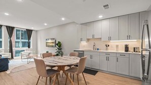 Eine moderne Küche mit weißen Schränken, einem Edelstahl-Kühlschrank und einem Essbereich mit rundem Tisch und Stühlen.