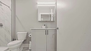 Ein modernes Badezimmer mit Toilette, Waschbecken mit Spiegel darüber und einer Duschkabine.