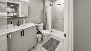 A modern bathroom with a toilet, sink, mirror, and shower. - Luxury 1BD | 3 Beds | Northern Liberties (Philadelphia)