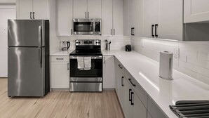 A modern kitchen with stainless steel appliances, white cabinetry, and a tiled backsplash. - Luxury 1BD | 3 Beds | Northern Liberties (Philadelphia)