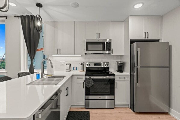 A modern kitchen with white cabinets, stainless steel appliances, and a large island.