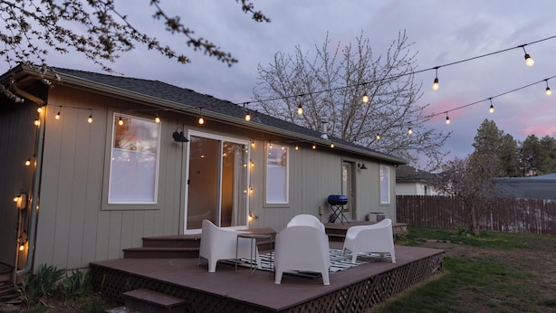 Ein Haus mit Terrasse, Sitzgelegenheiten im Freien und Lichterketten.