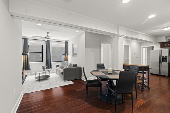 A modern kitchen with a refrigerator, dining table, and chairs.