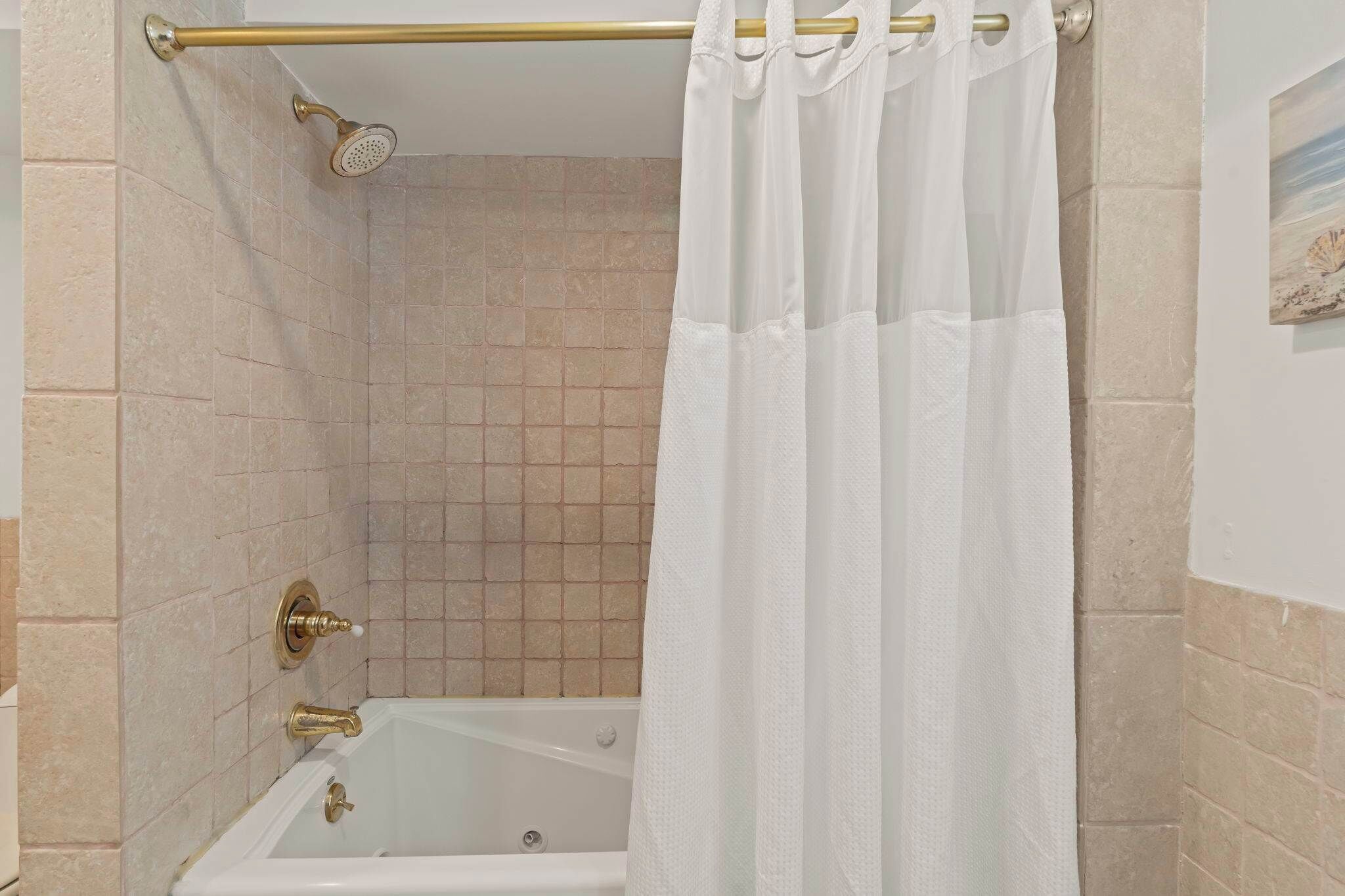 A bathroom with a bathtub, a showerhead, and a curtain.
