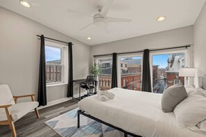 A modern hotel room with a large bed, a desk, and a view of the cityscape.