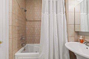 A bathroom with a bathtub, a shower, and a sink.