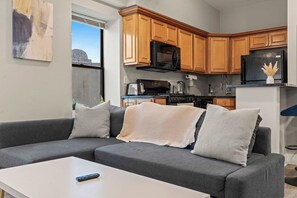 A modern kitchen with wooden cabinets, a black refrigerator, and a microwave.