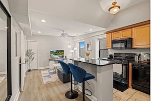 A modern kitchen with a central island, black appliances, and wooden cabinets.