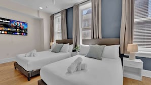 Habitación de hotel con dos camas, un televisor en la pared y una ventana con cortinas.