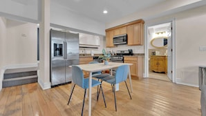 Una cocina moderna con electrodomésticos de acero inoxidable, un comedor con sillas azules y un armario de madera.