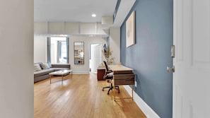 A modern living room with a sofa, coffee table, and a desk with a chair.