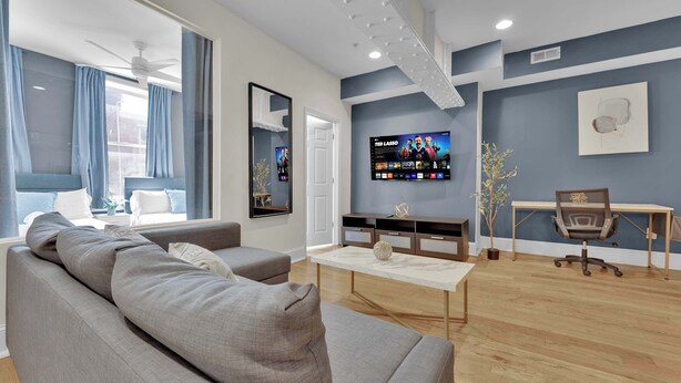 Una sala de estar moderna con un sofá, televisor y un espacio para escritorio.