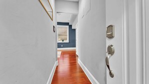 Un couloir doté d’un plancher en bois, de murs blancs, d’un mur d’accent bleu, et d’une porte avec un trou de serrure et une serrure.