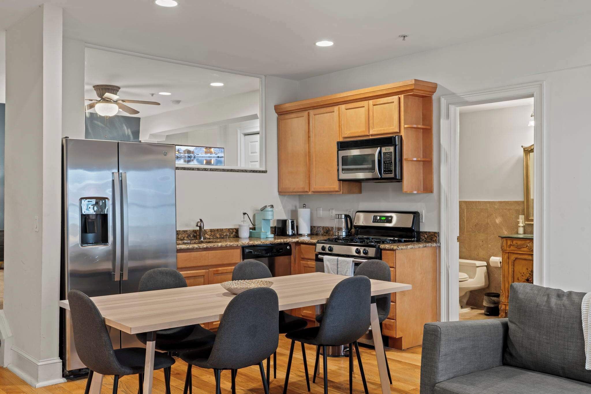 Cocina compacta equipada con refrigerador, microondas, estufa y mesa de comedor con sillas.