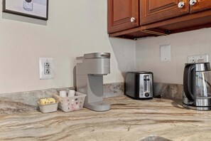 A kitchen counter with a coffee maker, toaster, and kettle.