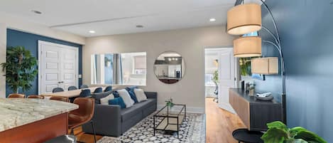 A modern living room with a sofa, coffee table, and dining area.