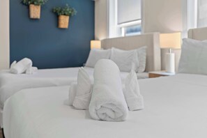 Hotellihuone, jossa on siististi pedattu sänky, sininen tehosteseinä ja yöpöydällä oleva lamppu.