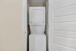 A white washer and dryer unit in a laundry room with a white door.