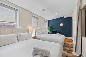 Ein Hotelzimmer mit zwei Betten, einem Schreibtisch, einem Stuhl, einer Lampe und Blick nach außen.