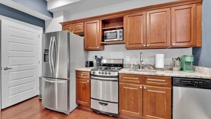 A kitchen with stainless steel appliances, wooden cabinets, a microwave, a stove, and a dishwasher. - Cozy Studio | Old City | 1Bed |Independence Hall (Philadelphia)