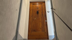 Une porte en bois, située en haut d’un escalier, avec un luminaire au-dessus.