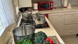 Une cuisine équipée d’un four à micro-ondes, d’une cuisinière et de divers ustensiles de cuisine.