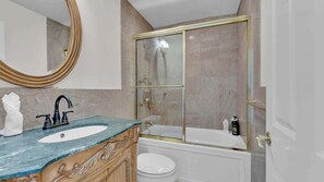 A bathroom with a marble sink, a bathtub, a toilet, and a glass-enclosed shower.