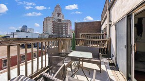 A balcony with wicker furniture, a view of a historic building, and a brick building in the background.
