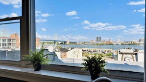 A view through a window with a river, buildings, and a bridge in the background.