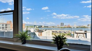 A view through a window with a river, buildings, and a bridge in the background.