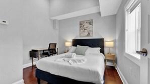 A neatly arranged bedroom with a bed, bedside tables, a chair, and a painting on the wall. - Bright 1BR Retreat | Sleeps 4 | by Liberty Bell (Philadelphia)