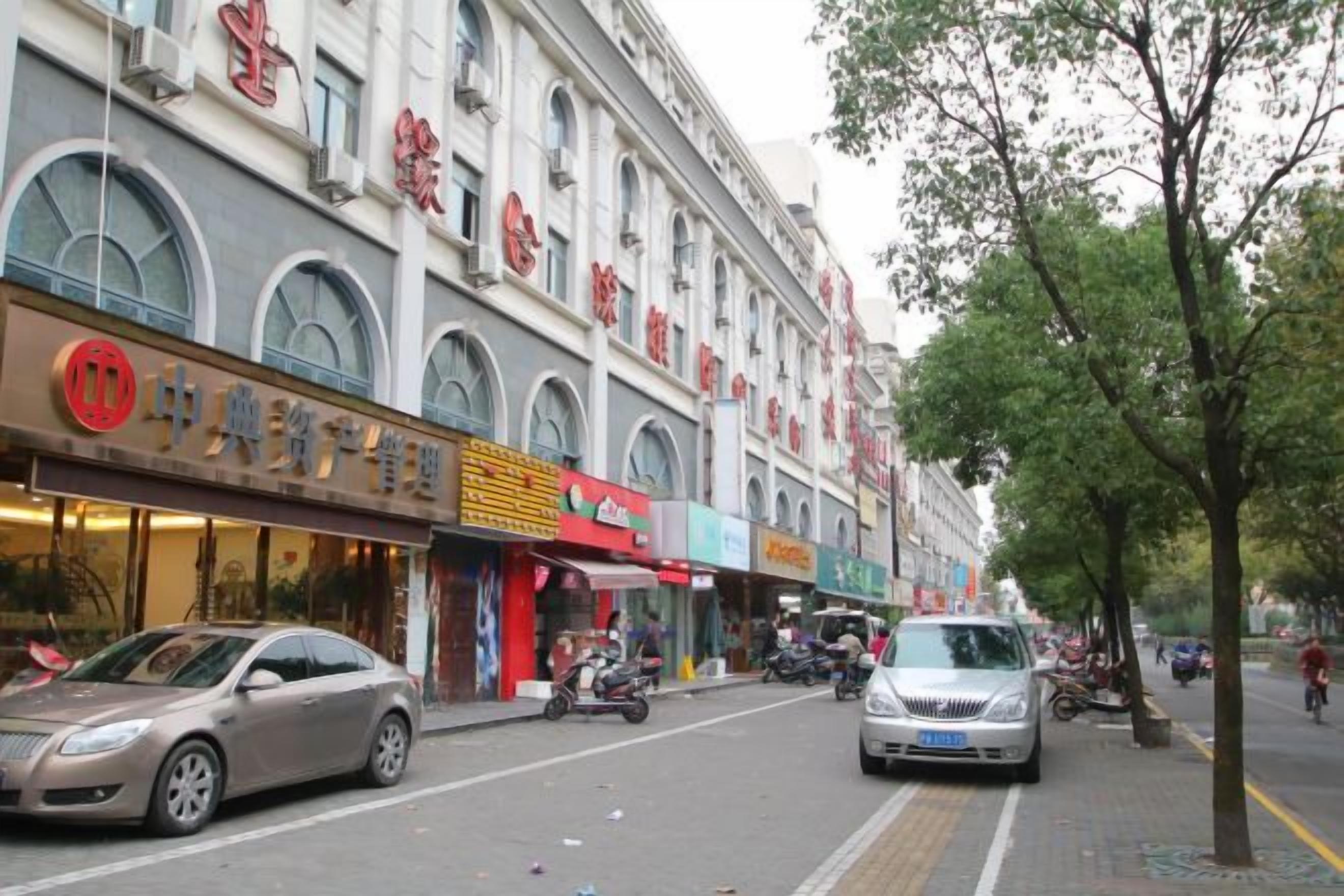 A street with shops and a car parked on the side.