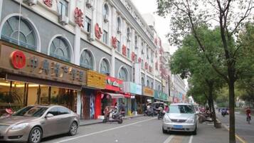A street with shops and a car parked on the side.