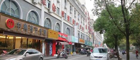 A street with shops and a car parked on the side.