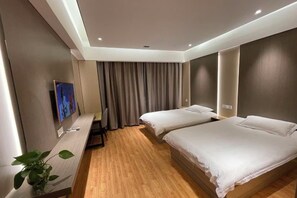 Une chambre d’hôtel moderne équipée de deux lits, d’une télévision, d’un bureau et d’une plante.