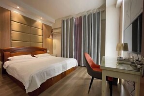 A hotel room with a wooden bed, a desk with a chair, a television, and a window with curtains.