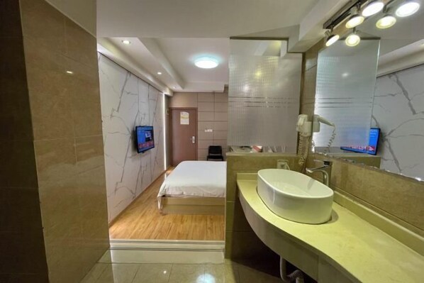 Une salle de bain moderne avec un grand miroir, un lavabo et un lit.