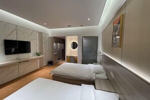 Une chambre d’hôtel moderne équipée d’une télévision, de deux lits, d’un coin cuisine et d’une salle de bain.