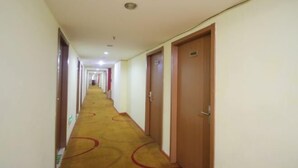 Un pasillo de hotel con puertas a ambos lados, suelo alfombrado e iluminación en el techo.