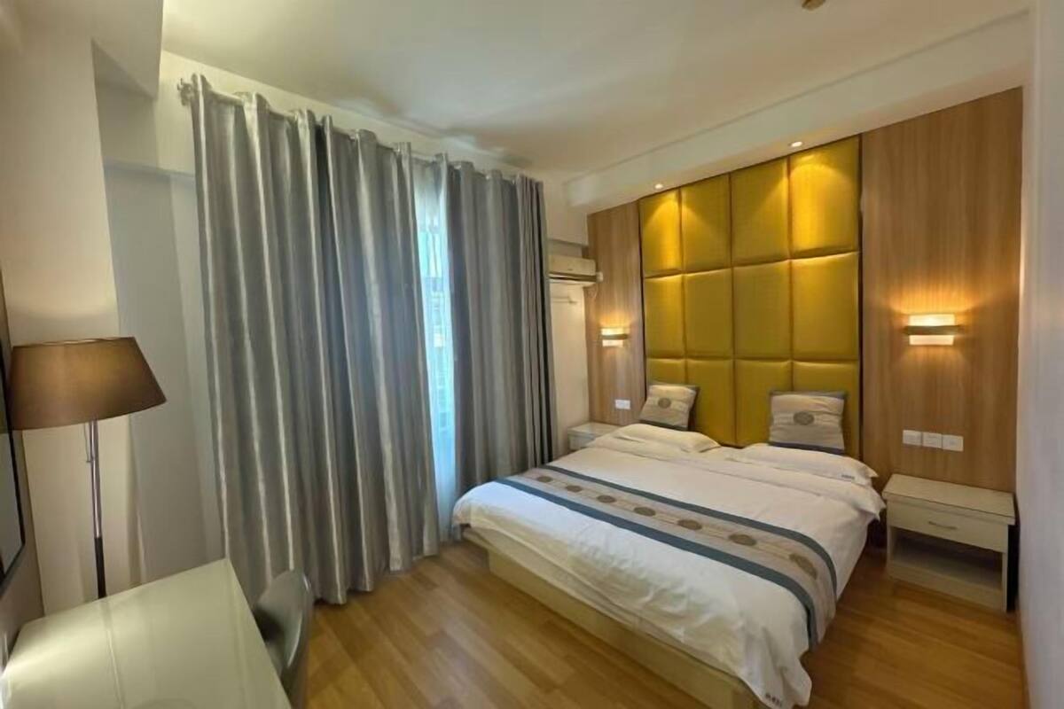 Een hotelkamer met een groot bed, een nachtkastje, een lamp en een wandlamp.