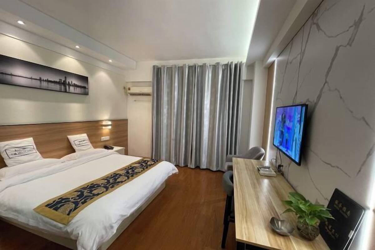Een hotelkamer met een bed, bureau, televisie en raam met gordijnen.