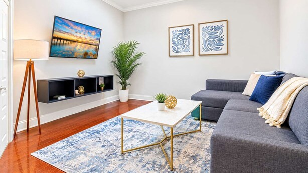 Un salon moderne comprenant un canapé, une table basse, un lampadaire, un tableau et deux œuvres d’art encadrées.