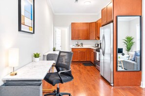 A modern kitchen with wooden cabinets, a stainless steel refrigerator, and a dining area with a table and chairs.