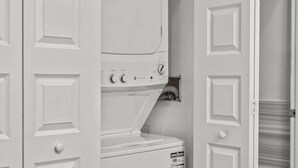 A laundry room with stacked washers and dryers, a door with a handle, and a wooden floor. - Luxury 1BD | 2 Beds | Queens Village (Philadelphia)